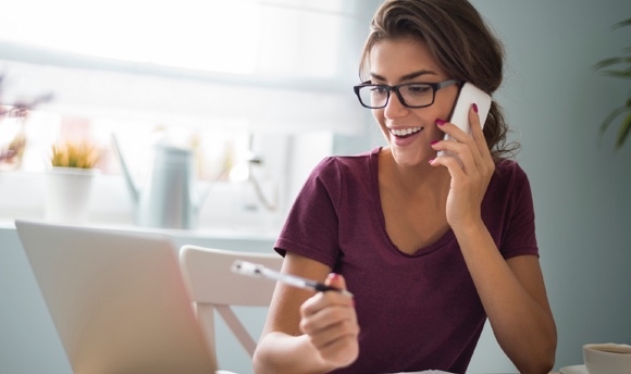 Image of a smiling young woman on the phone with a client